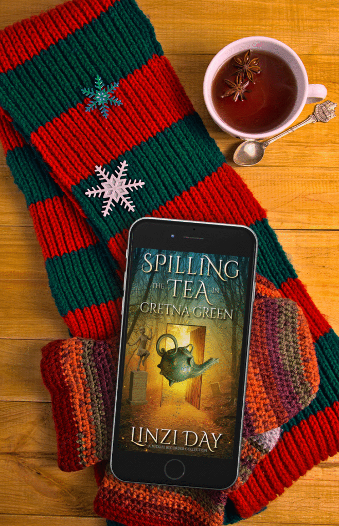 The Spilling the Tea ebook on a phone with woollen Christmas stockings and a cup of tea.